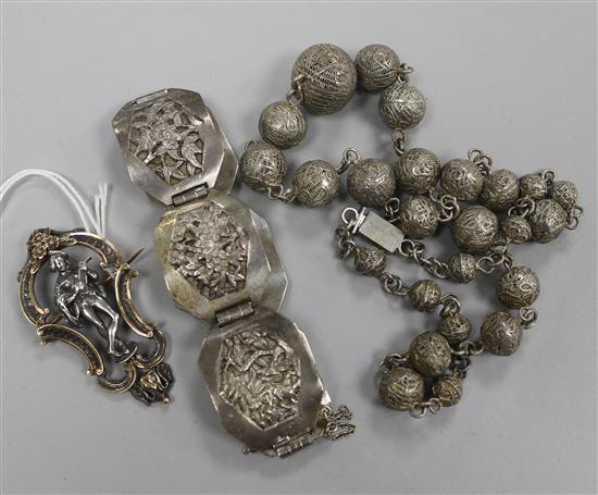 An early 20th century French silver and 18ct gold figural brooch with scrolling border, a Chinese bracelet and a necklace